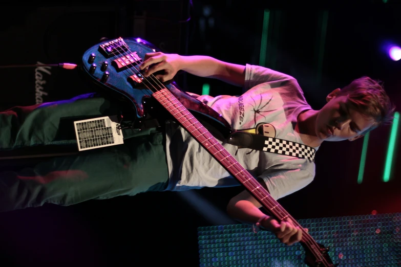 a young man holding onto a blue guitar