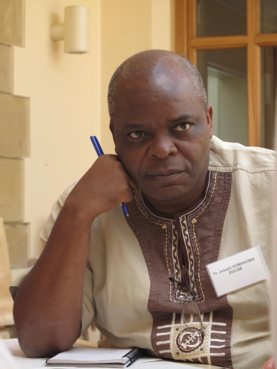 an older man with a pen sits at a table