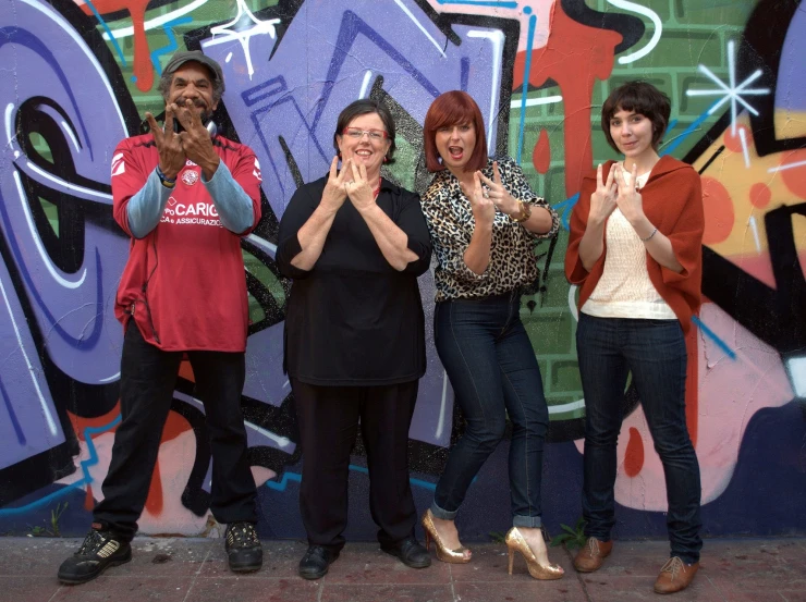 four women standing in front of a graffiti wall