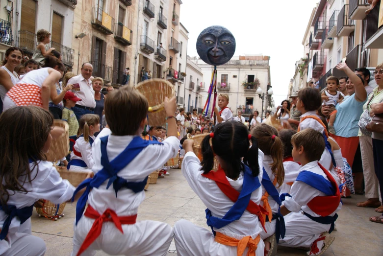 children are in an outdoor parade, while adults watch