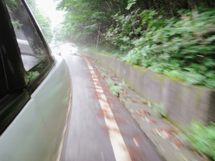 a car moving down a rural road with some trees