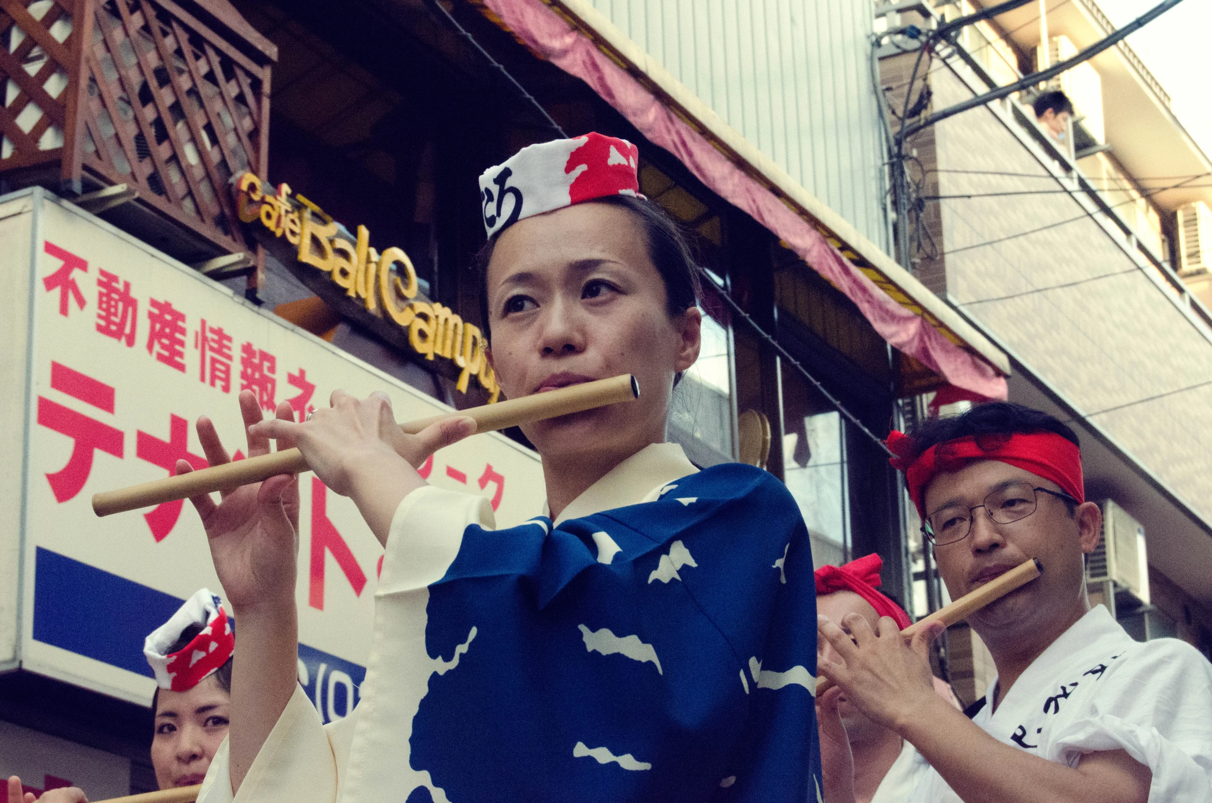 a young lady dressed up playing a bamboo flute