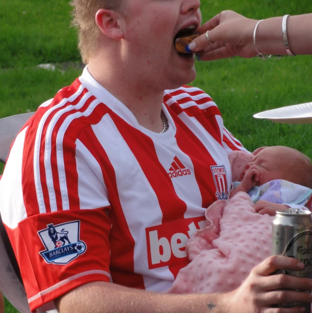 a person feeding another persons food over a baby