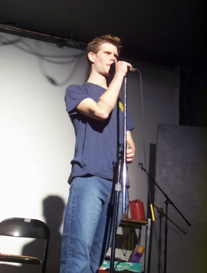 a young man standing on stage holding up his microphone