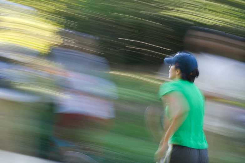 an blurry image of a man in a green shirt holding a tennis racket