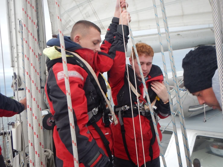 two people standing around a sailboat at the helm