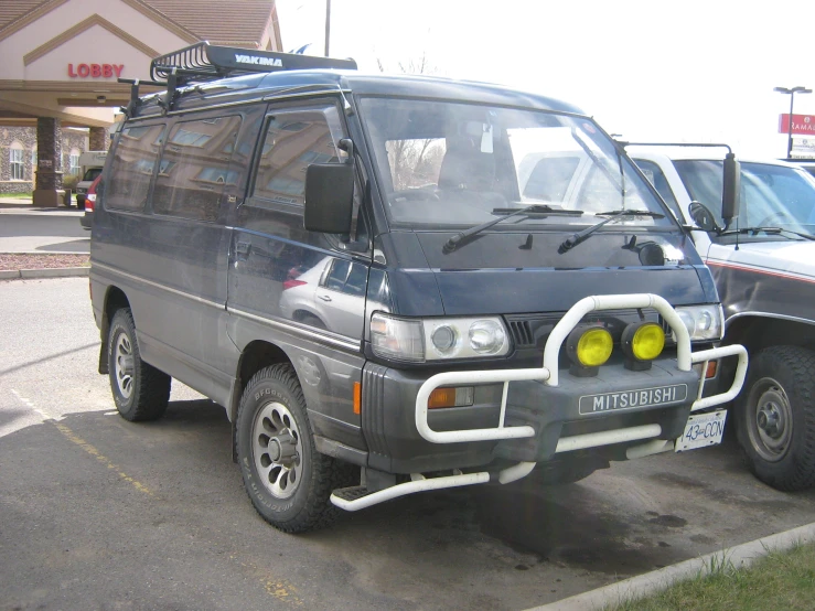 the small van is parked in a parking lot