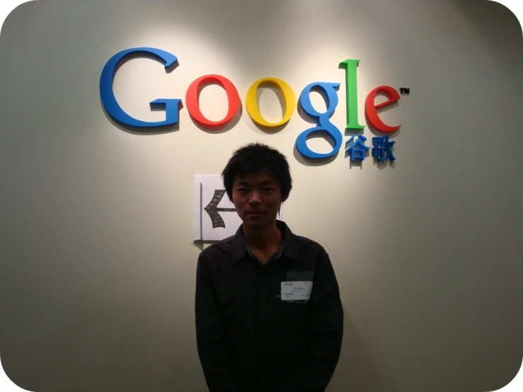 a man standing next to a wall with google signs on it