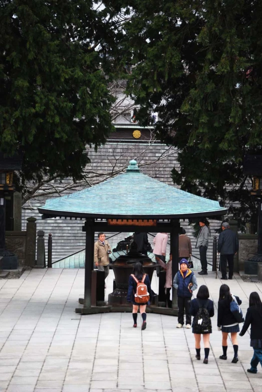 several children in uniforms are walking towards a shrine