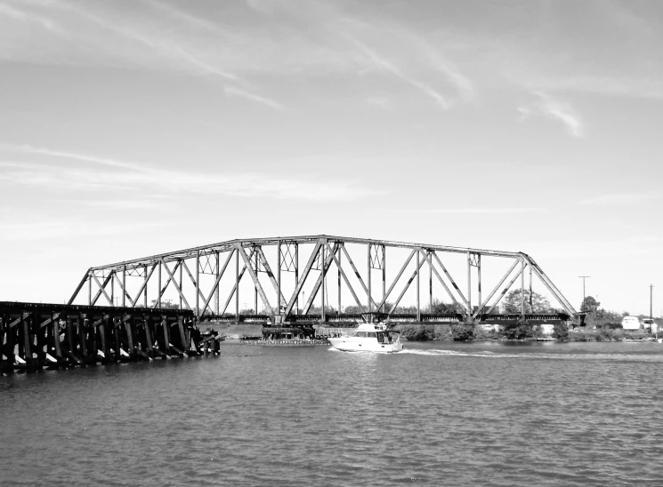 an old bridge spanning a waterway next to boats