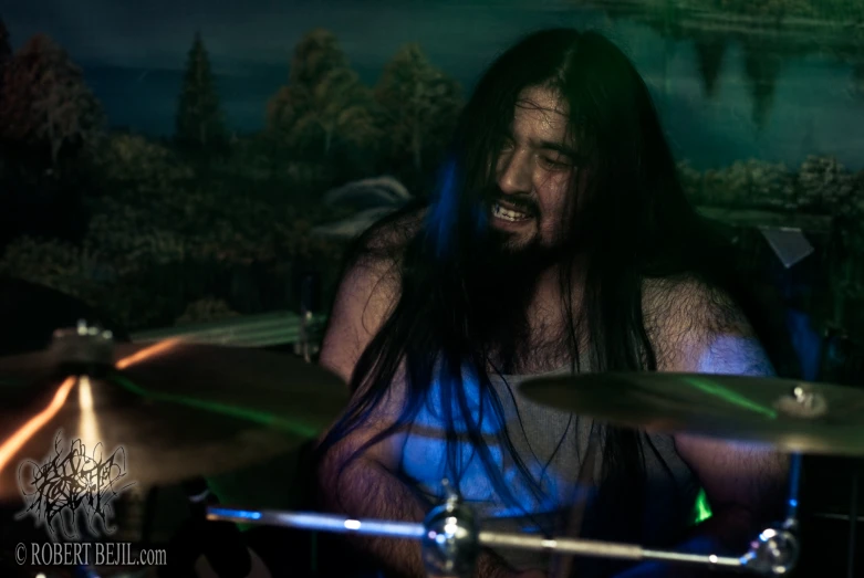 there is a man with long hair on a drumset