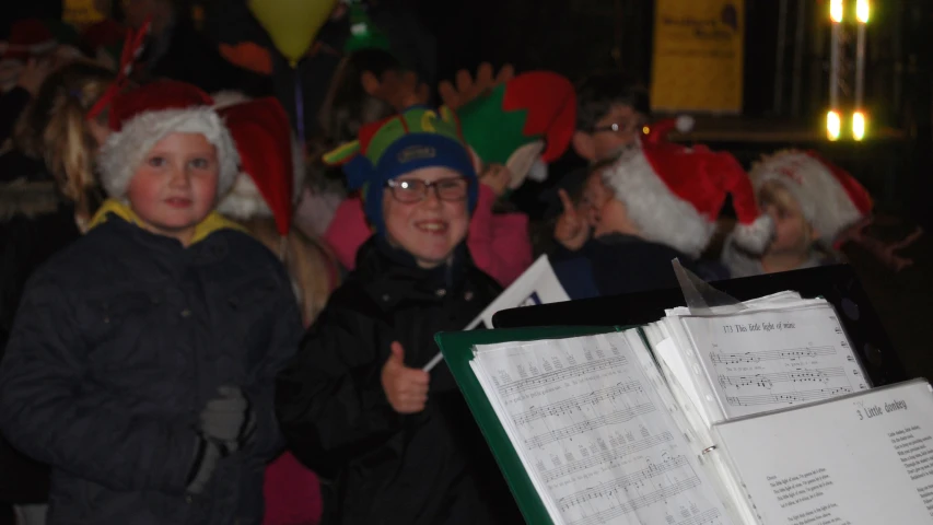 a group of children in santa hats sing and play