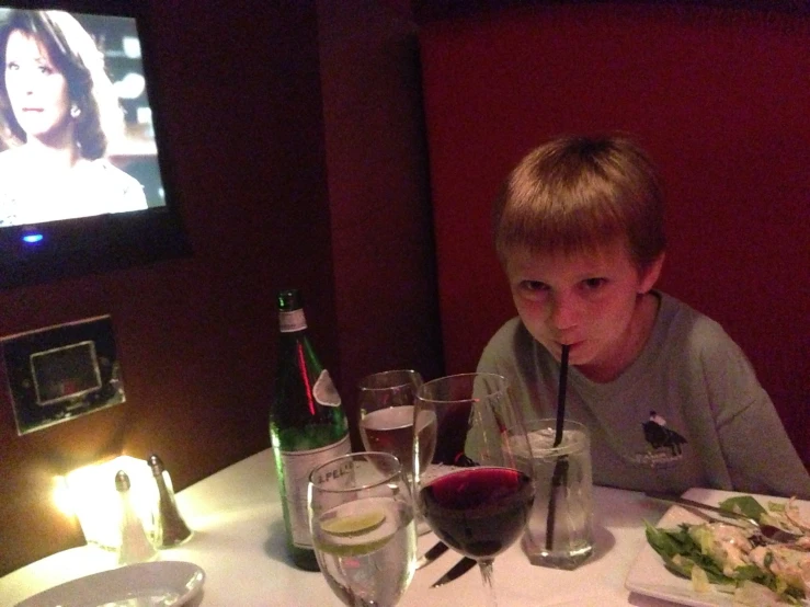 a child sitting at a table eating and watching television