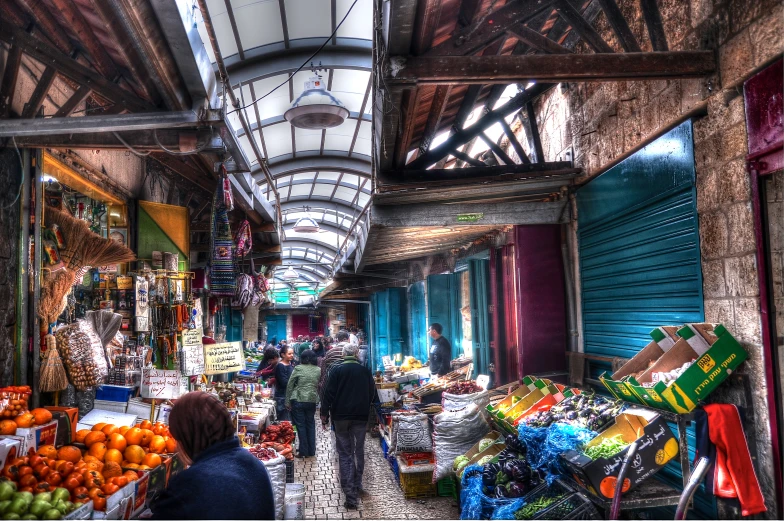 a market has fruit, vegetables and people shopping in it