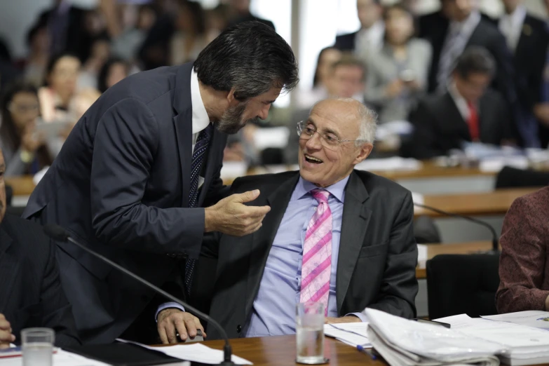 two men are talking while sitting at a table