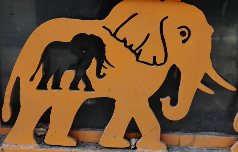 an elephant and baby elephant are silhouetted against the wall