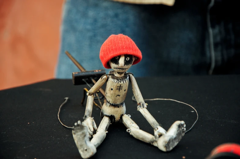 a skeleton holding a small gun and wearing a red cap