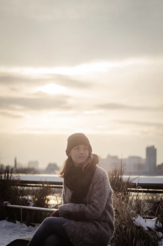 a woman sitting on top of a black bench next to snow