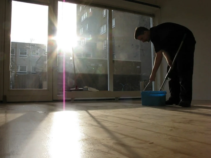 man sweeping the floor with a mop in a living room