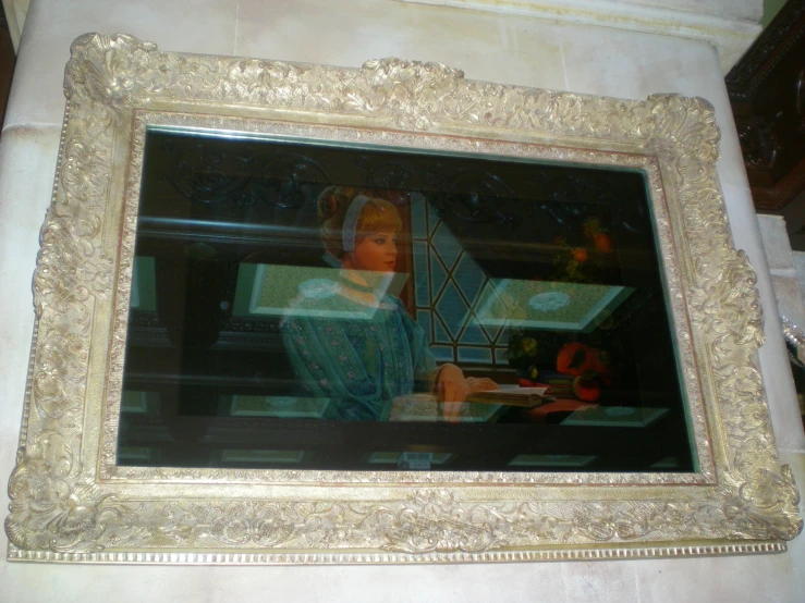 an ornate wooden frame holding a painting in the shape of a girl