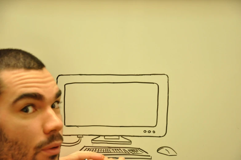 a man drawing on a wall with a monitor and keyboard