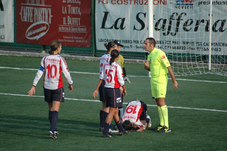 three women in uniforms talking to a referee on the field