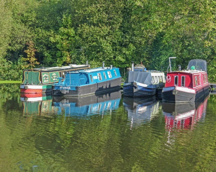 four narrow boats are docked on the river
