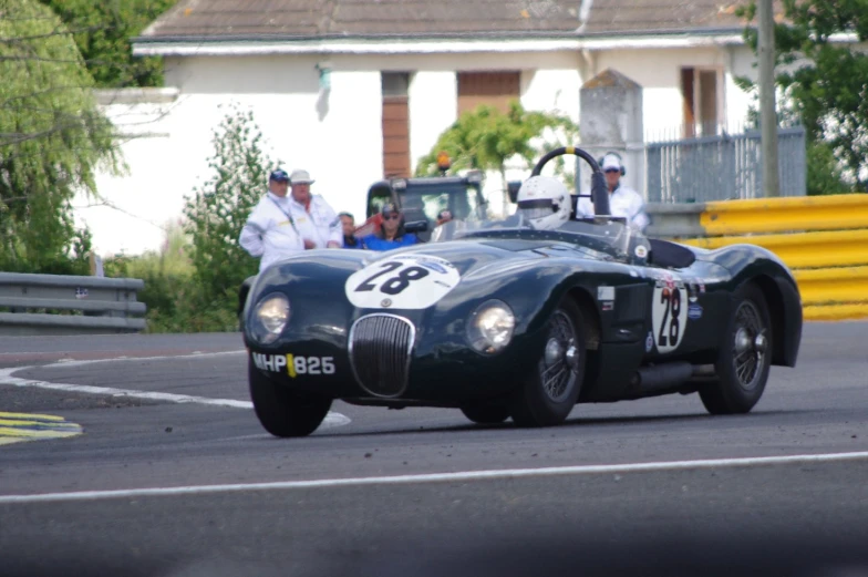 two men ride in an antique racing car