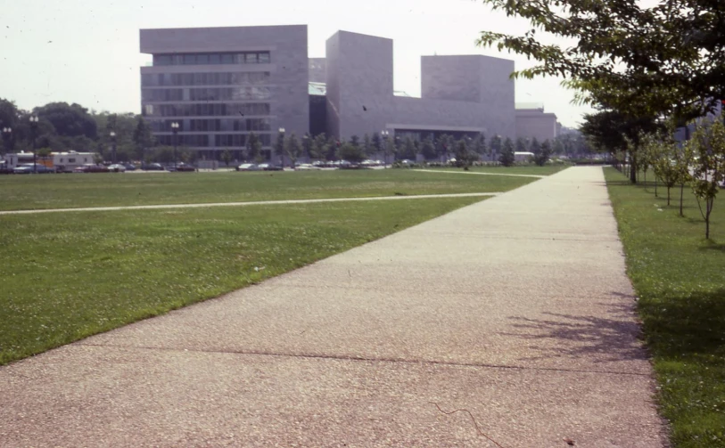 a walk way leads out towards an area with trees, grass and buildings