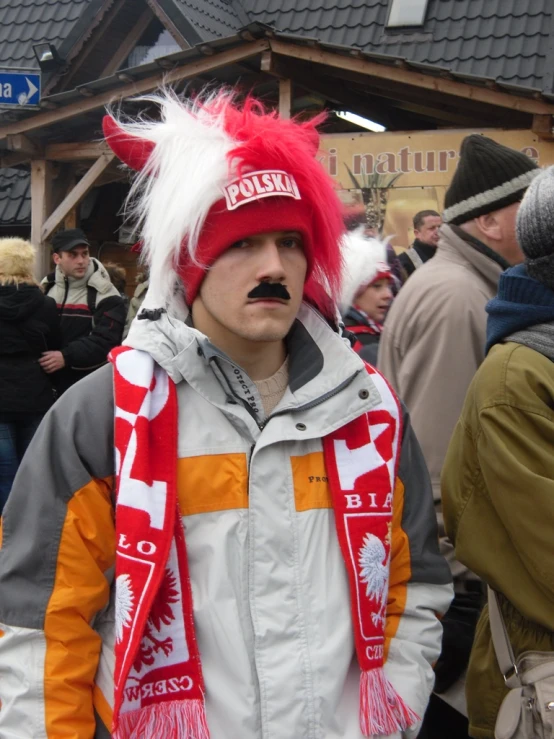 a man with an orange and white scarf and red hat