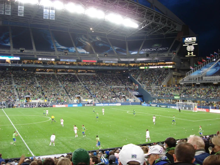 several players play soccer on an illuminated soccer field
