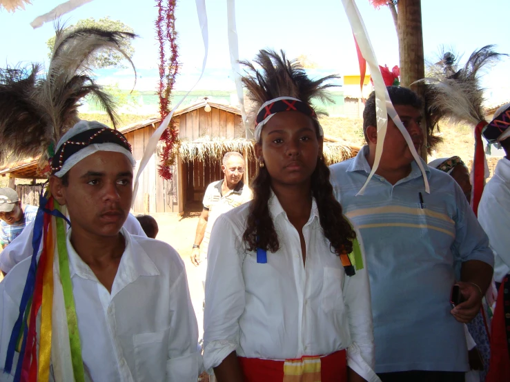 two women in native clothing stand between three men in headdress