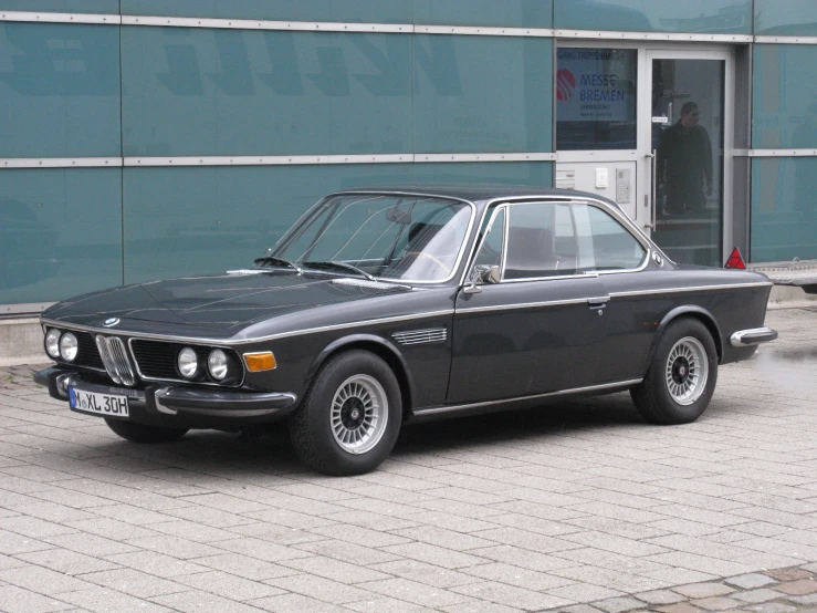 this bmw coupe is parked outside a building