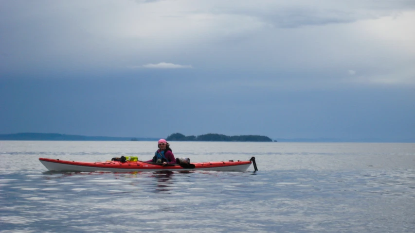 the person is paddling their small boat across the calm water