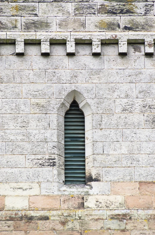 a tall brick building with a small window near a wall