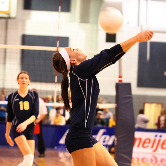 a girl hits the volleyball over a net