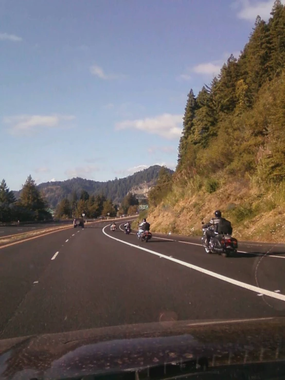 several people riding motorcycles down the road