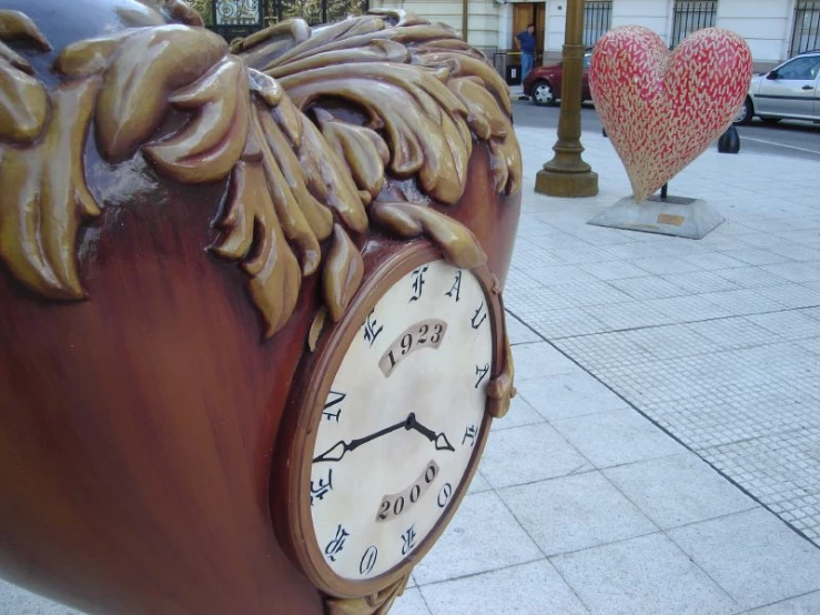 a clock is sitting on the curb beside hearts