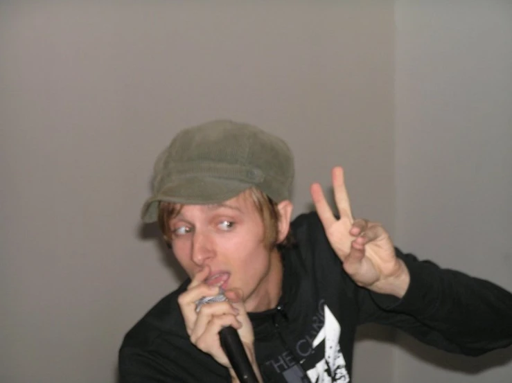 a young man is holding up two fingers and making the peace sign