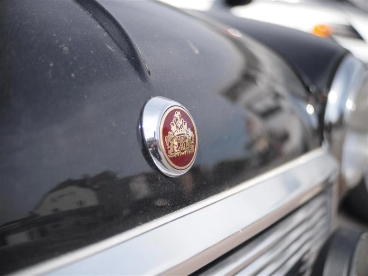 the badge on a old black car that is parked