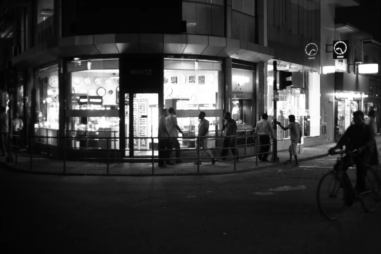 people standing and sitting around on the street corner at night