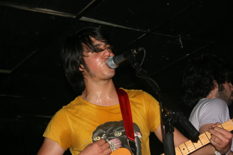 a man playing a guitar while a microphone stands in the background