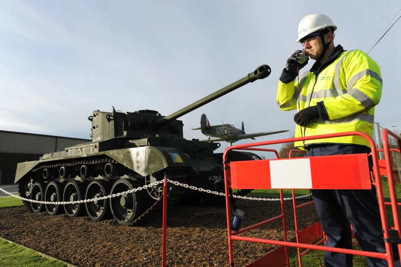 a man with a safety jacket is next to an army tank