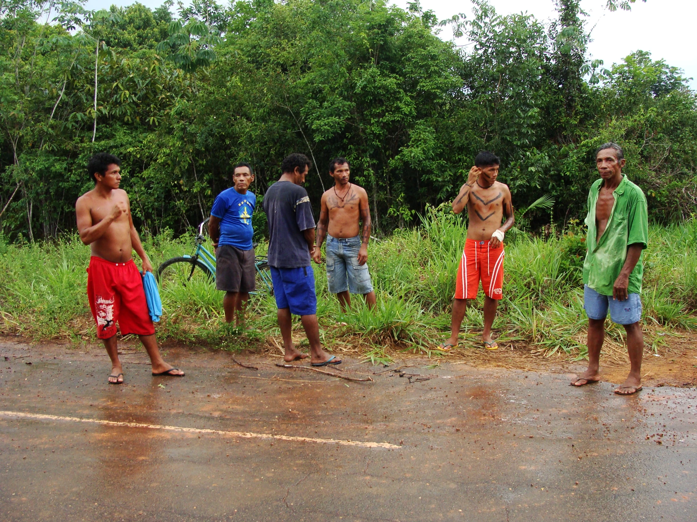 four men in short shorts are standing on a wet road