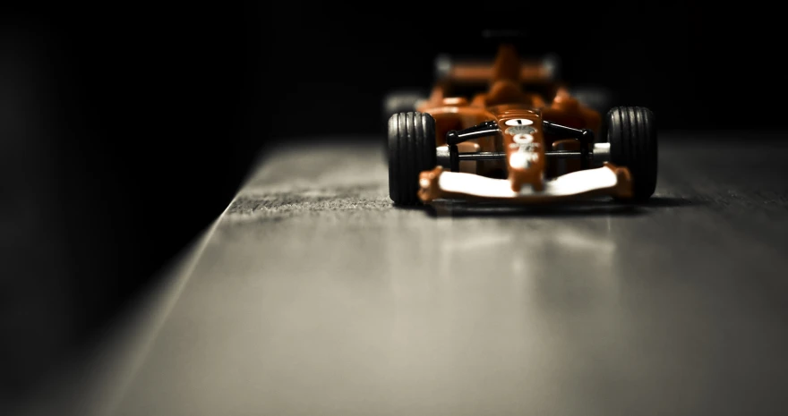 the orange racing car is parked on a concrete surface