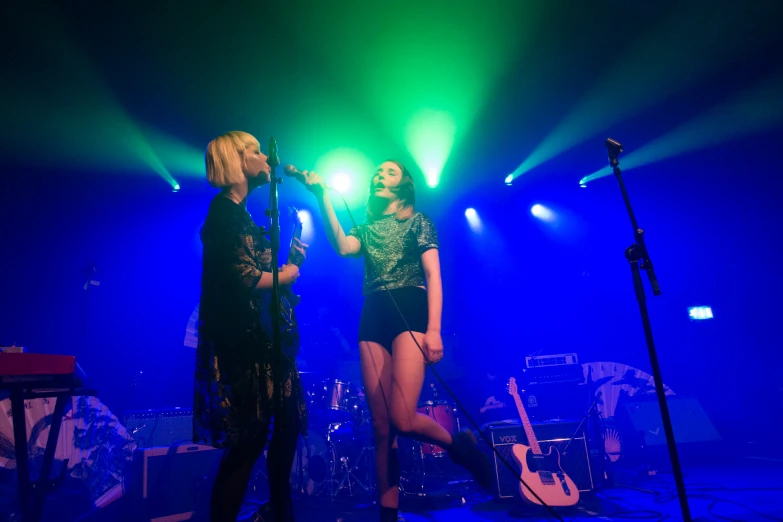 two people standing on stage with green lights