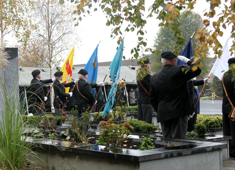 a bunch of men wearing coats holding a flag