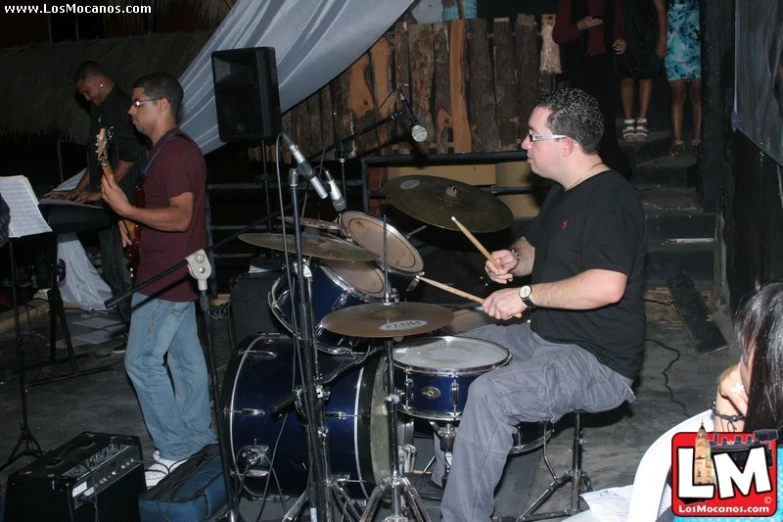 a man on the drums while someone on the stage plays drums