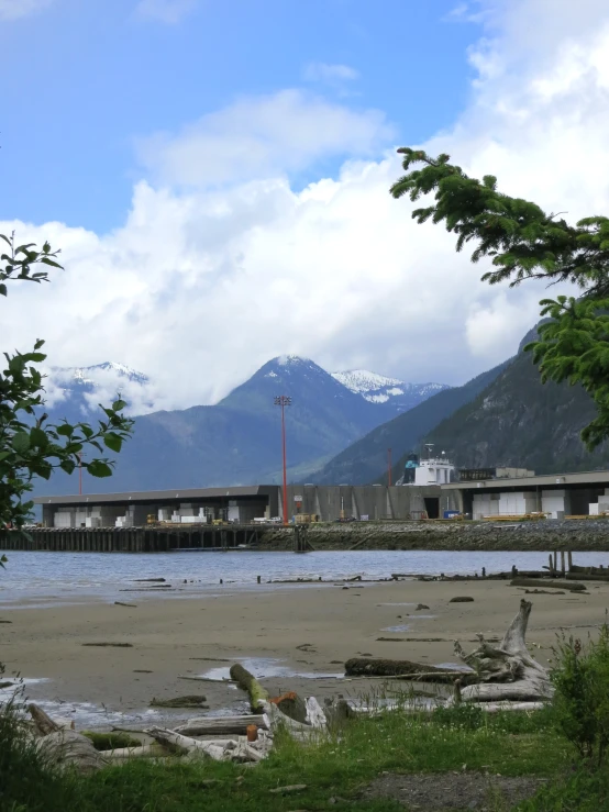 some buildings and mountains and water under a cloudy sky