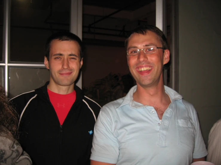 two smiling men in glasses standing beside each other